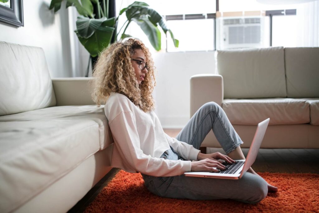 beautiful girl sitting on the floor on her laptop wearing casual clothes