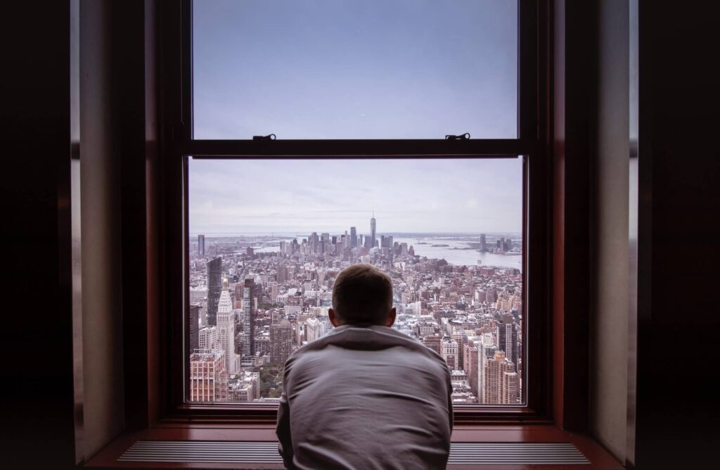 why learn spanish - man looking out of an apartment window at ney york city