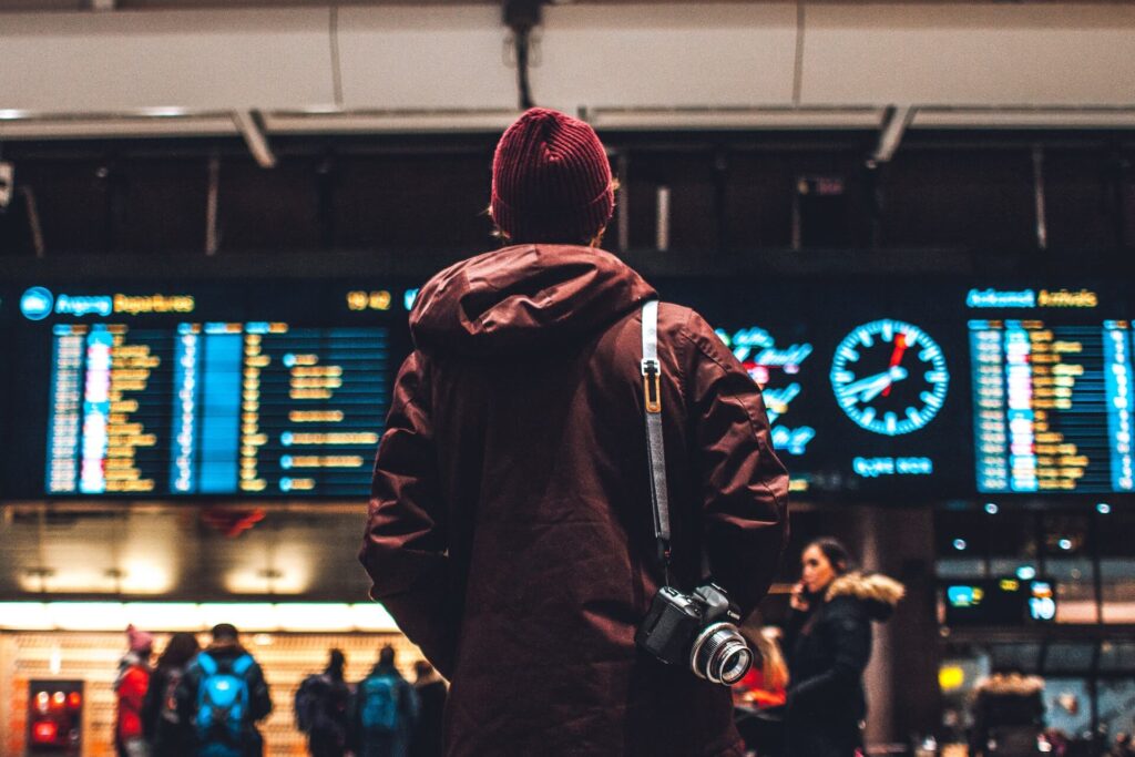 man standing in front of a flight board at the airport