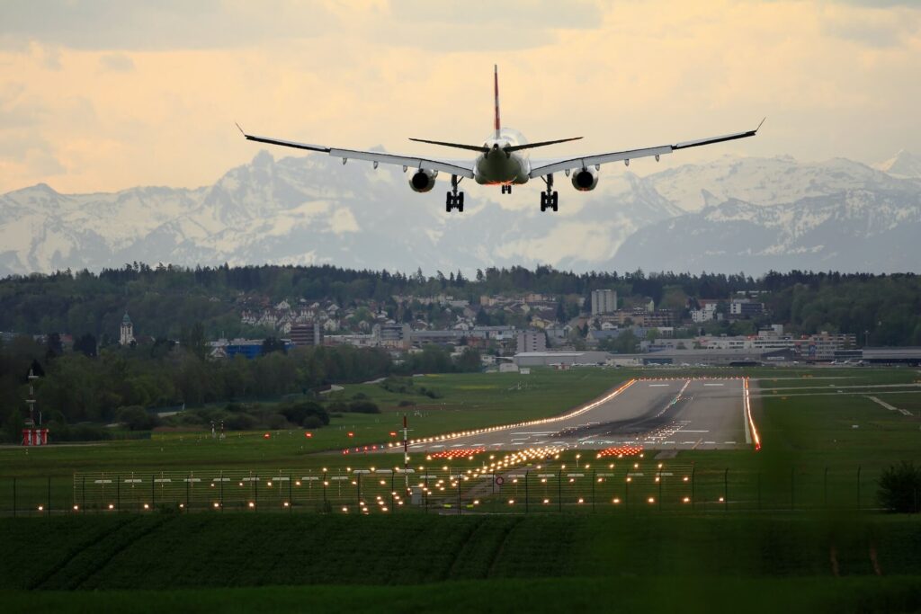 plane landing on a runway in front of moutains